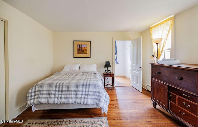 bedroom featuring hardwood / wood-style floors and a baseboard heating unit