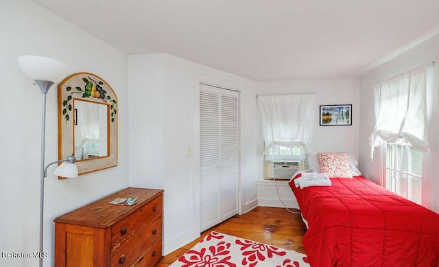 bedroom featuring cooling unit, light wood-type flooring, multiple windows, and a closet