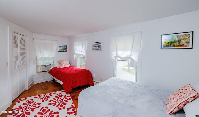 bedroom with cooling unit, wood-type flooring, baseboard heating, and a closet