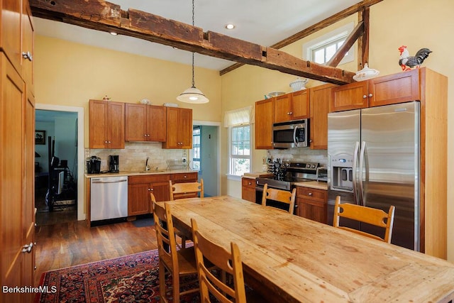 kitchen with pendant lighting, sink, tasteful backsplash, beam ceiling, and stainless steel appliances