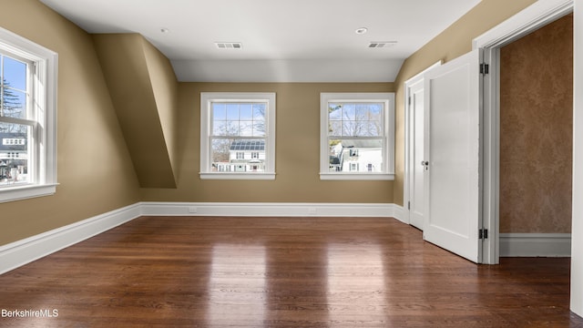 spare room with wood finished floors, visible vents, and baseboards