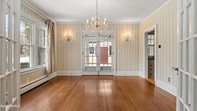 unfurnished room featuring a baseboard heating unit, a healthy amount of sunlight, and wood-type flooring