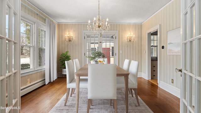 dining room featuring a notable chandelier, baseboard heating, crown molding, and wood finished floors