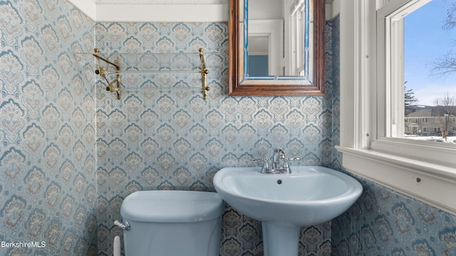 half bathroom with wallpapered walls and toilet