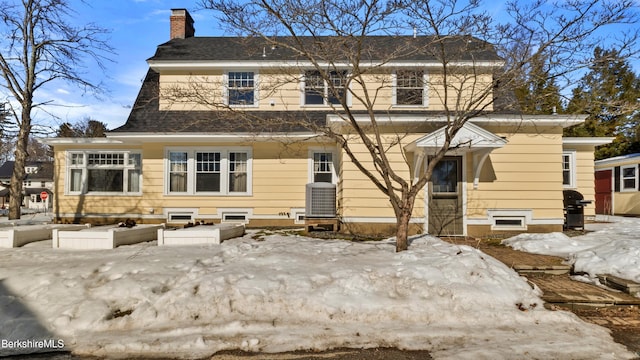 rear view of property with cooling unit and a chimney