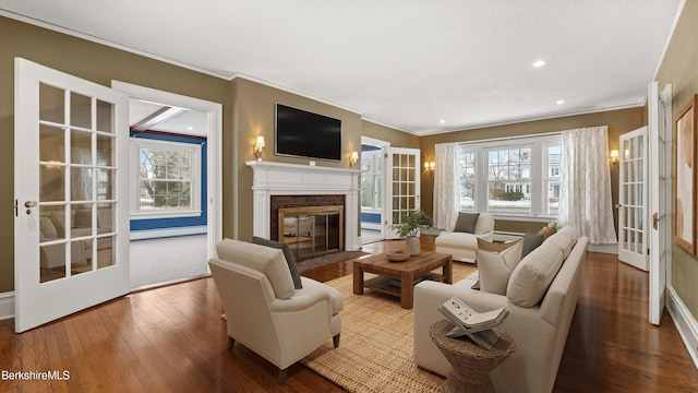 living room featuring a fireplace, french doors, wood-type flooring, a baseboard heating unit, and crown molding