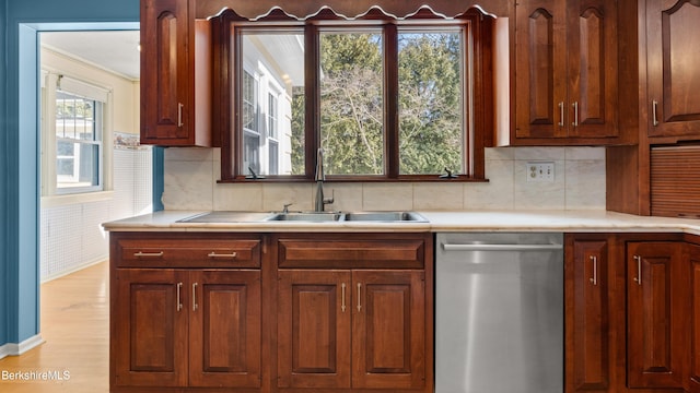 kitchen featuring decorative backsplash, dishwasher, light countertops, and a sink