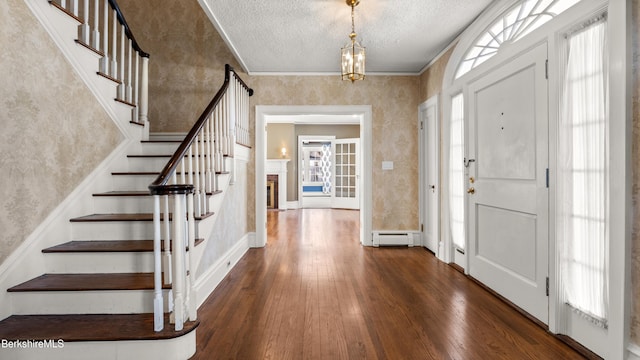 entryway with a baseboard heating unit, wood-type flooring, a textured ceiling, and a healthy amount of sunlight