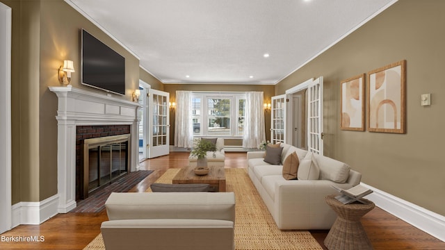 living area featuring ornamental molding, a brick fireplace, baseboards, and wood finished floors