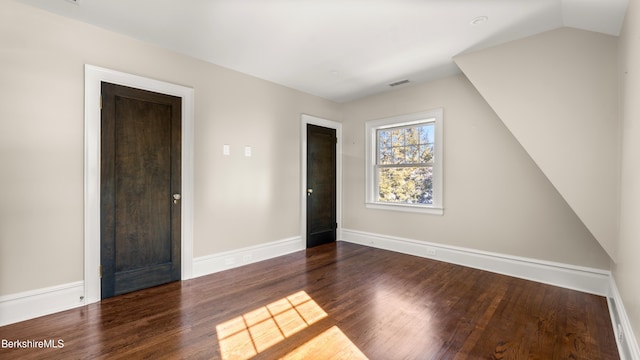 interior space featuring vaulted ceiling, wood finished floors, visible vents, and baseboards