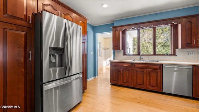 kitchen featuring a sink, stainless steel appliances, crown molding, light countertops, and decorative backsplash