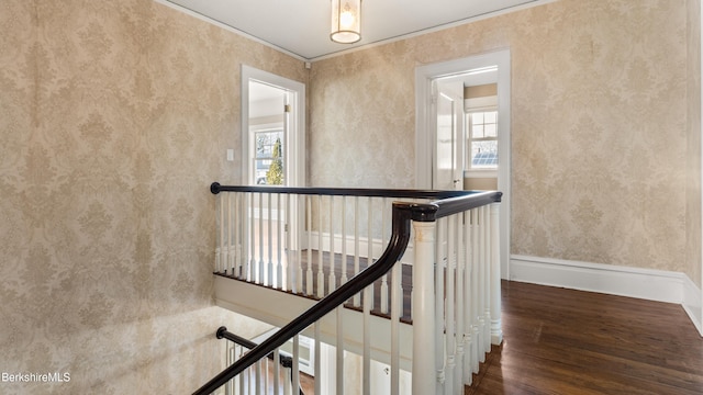 staircase with wallpapered walls, plenty of natural light, wood finished floors, and baseboards