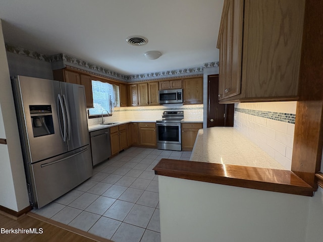 184 Mcintosh Dr, Pittsfield, MA 01201 - kitchen with appliances with stainless steel finishes, tasteful backsplash, a peninsula, and light tile patterned flooring