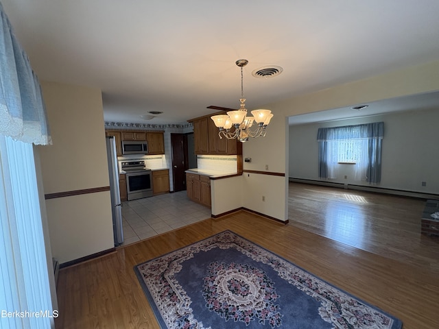184 Mcintosh Dr, Pittsfield, MA 01201 - kitchen with appliances with stainless steel finishes, a chandelier, light wood-type flooring, backsplash, and a baseboard heating unit