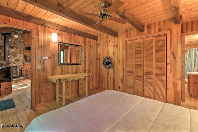 bedroom with beamed ceiling, wooden walls, wooden ceiling, and hardwood / wood-style floors