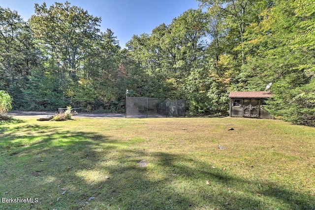 view of yard featuring an outbuilding, fence, and a wooded view