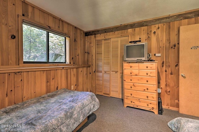 carpeted bedroom featuring wood walls and a closet