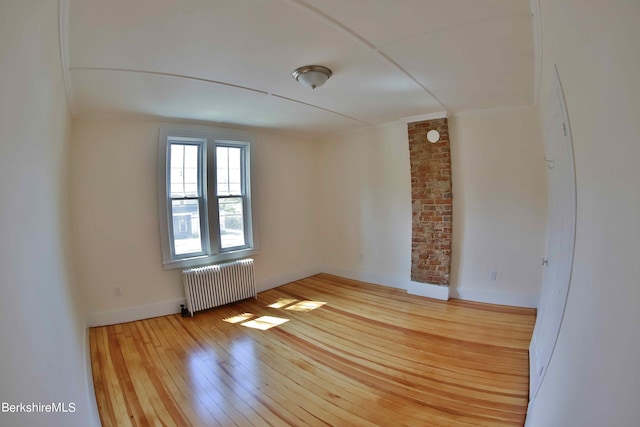 spare room with light hardwood / wood-style floors and radiator heating unit