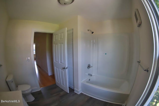 bathroom with shower / bathing tub combination, hardwood / wood-style flooring, and toilet