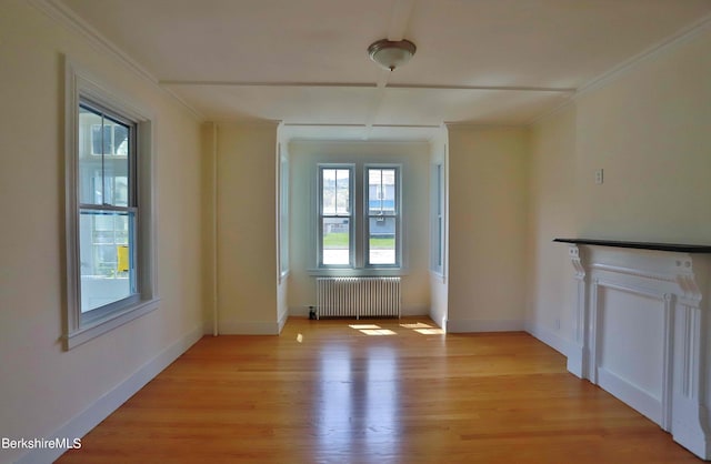 unfurnished living room with ornamental molding, radiator heating unit, a healthy amount of sunlight, and light hardwood / wood-style floors