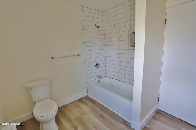 bathroom with tiled shower / bath combo, toilet, and wood-type flooring