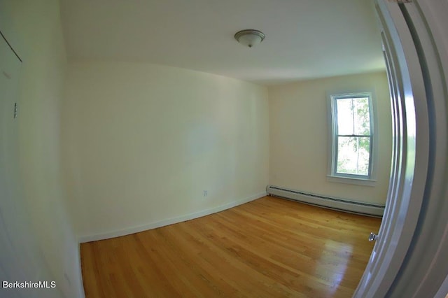 empty room featuring a baseboard radiator and light hardwood / wood-style floors