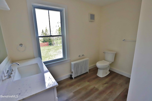 bathroom featuring hardwood / wood-style floors, vanity, toilet, and radiator