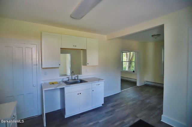 kitchen with dark hardwood / wood-style flooring, white cabinetry, baseboard heating, and sink