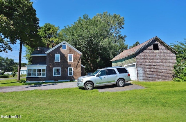 view of side of home with a garage, an outdoor structure, and a yard