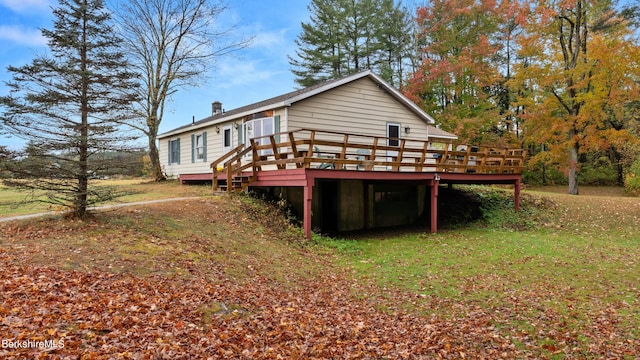 rear view of house featuring a wooden deck and a yard