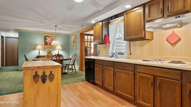 kitchen featuring pendant lighting, white cooktop, black dishwasher, sink, and a center island