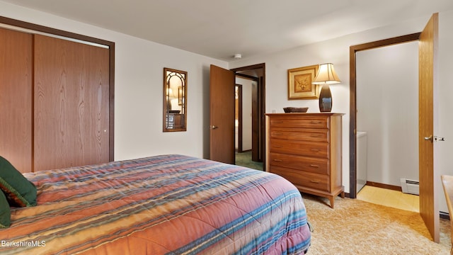 bedroom with a baseboard heating unit, light colored carpet, and a closet