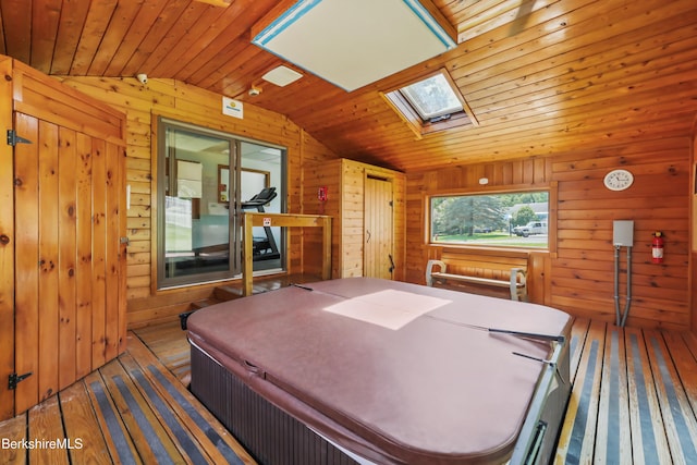 bedroom with vaulted ceiling with skylight, wooden ceiling, wood walls, and wood finished floors