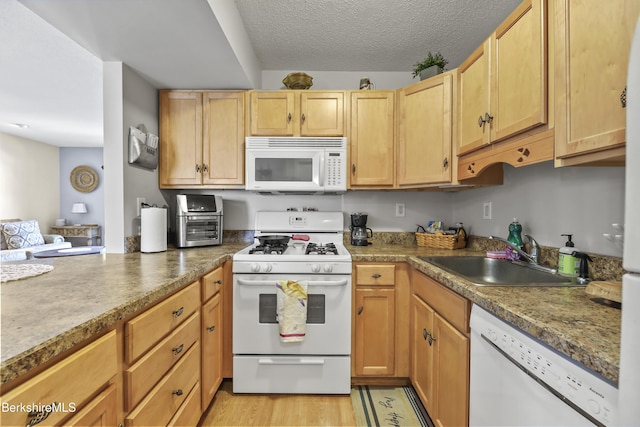 kitchen with white appliances, light wood-style flooring, a textured ceiling, and a sink