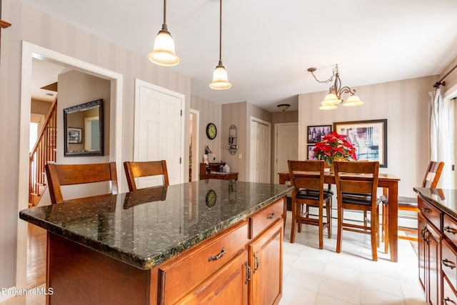 kitchen featuring hanging light fixtures, a center island, dark stone countertops, and an inviting chandelier