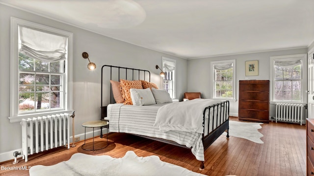 bedroom featuring radiator, hardwood / wood-style floors, and ornamental molding