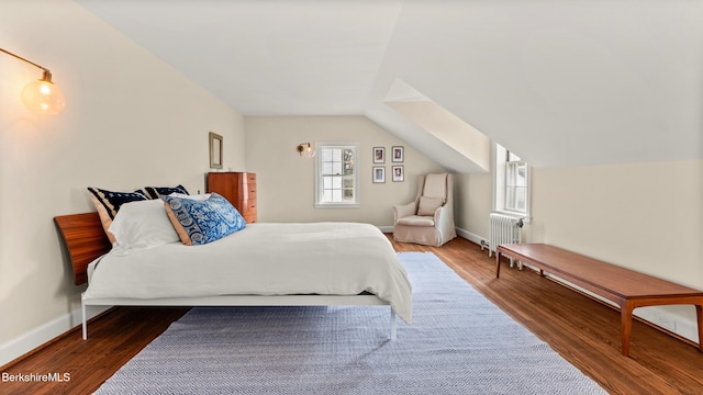 bedroom with wood-type flooring, vaulted ceiling, and radiator