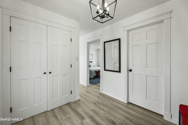 unfurnished bedroom with a closet, light hardwood / wood-style flooring, and an inviting chandelier