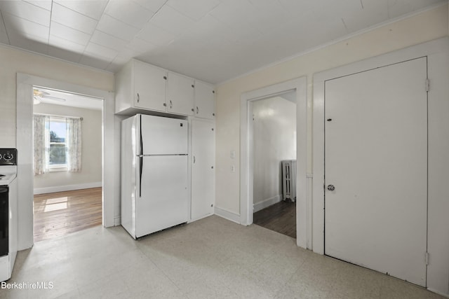 20 Summer St, Lee, MA 01238 - kitchen with light floors, radiator, baseboards, white cabinetry, and freestanding refrigerator