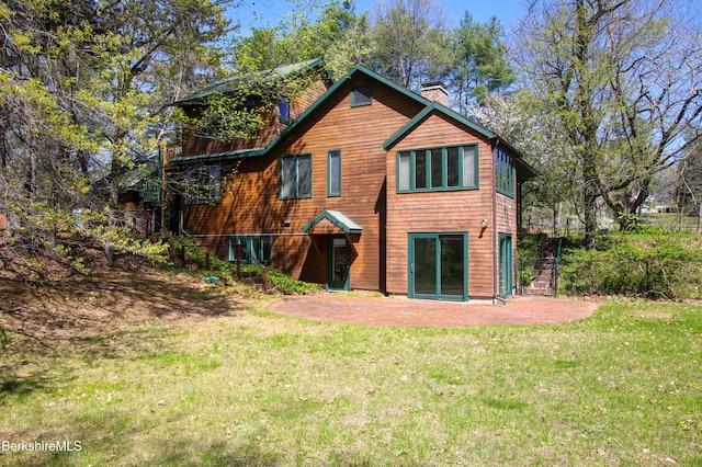 back of house with a chimney, a yard, and a patio area