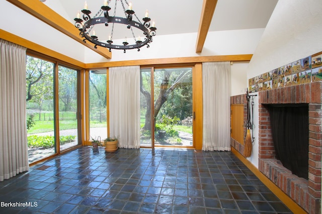 unfurnished living room featuring an inviting chandelier, high vaulted ceiling, a fireplace, and stone tile floors