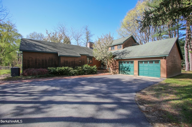 view of side of home featuring an attached garage, aphalt driveway, and a chimney