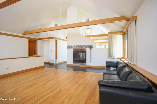 living area with baseboards, high vaulted ceiling, wood finished floors, and a tile fireplace