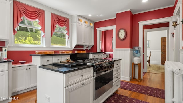 2 Melrose St, Adams, MA 01220 - kitchen with stainless steel range with gas stovetop, white cabinets, light wood-style floors, a wainscoted wall, and dark countertops