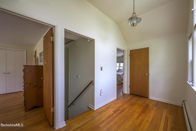 interior space with a baseboard heating unit, baseboards, an upstairs landing, and light wood-style flooring
