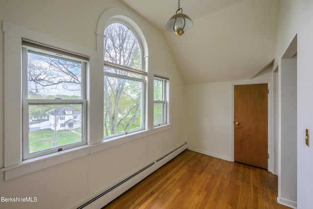 interior space with vaulted ceiling, wood finished floors, and a baseboard heating unit