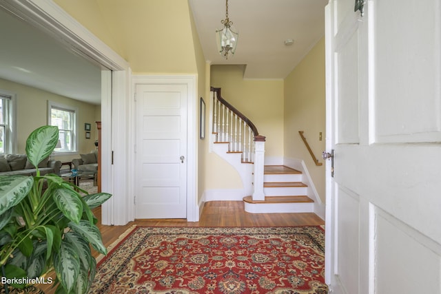 foyer featuring baseboards, stairway, and wood finished floors