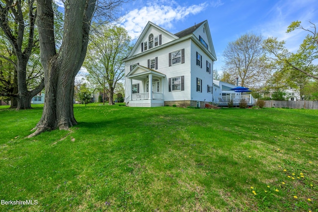 view of front facade with a porch, fence, and a front lawn