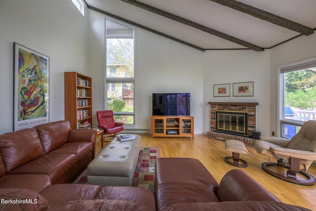 living area featuring a baseboard heating unit, a brick fireplace, vaulted ceiling with beams, and wood finished floors