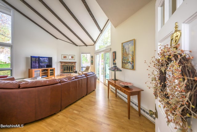 living area with a baseboard radiator, light wood finished floors, a brick fireplace, high vaulted ceiling, and beamed ceiling